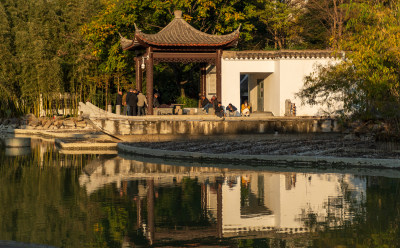 水边中式亭子旁有人闲坐的场景