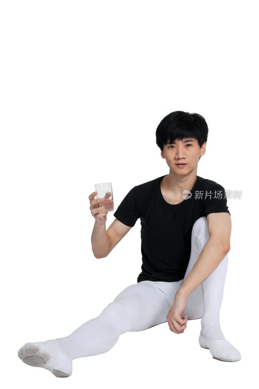 棚拍年轻的芭蕾舞男演员坐在地上喝水休息