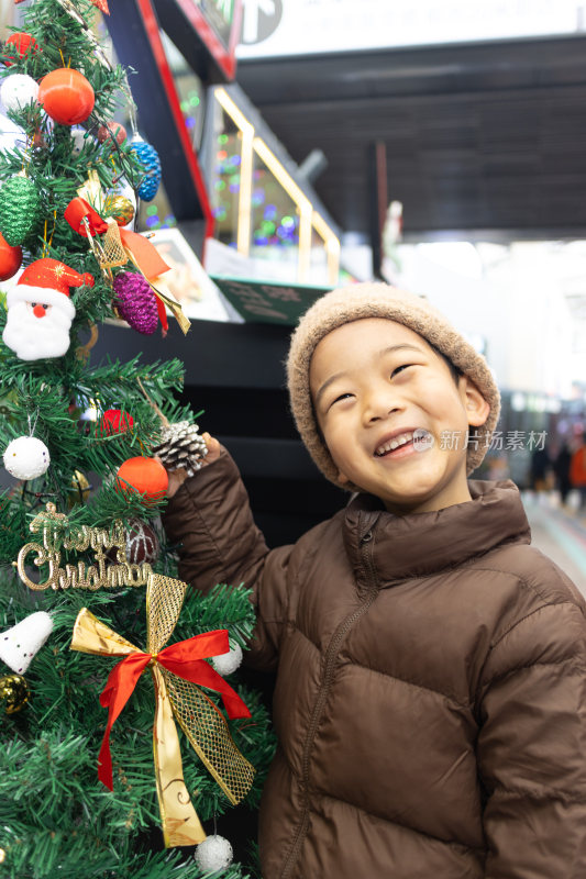 一个小男孩站在圣诞树旁边