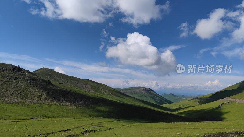 蓝天白云下的辽阔绿色山地风景