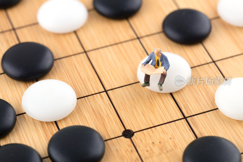 坐在棋盘棋子上看书的人偶