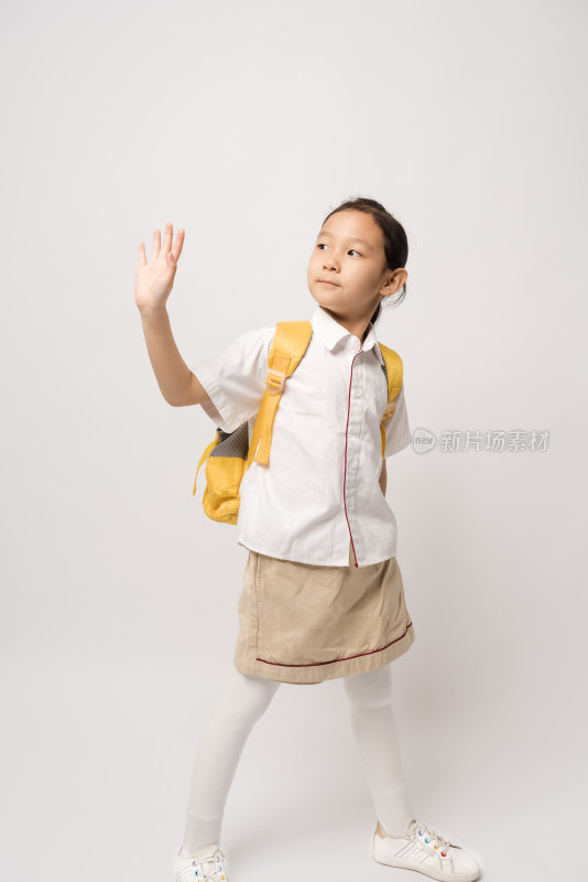 白色背景前穿校服挥手的中国女孩