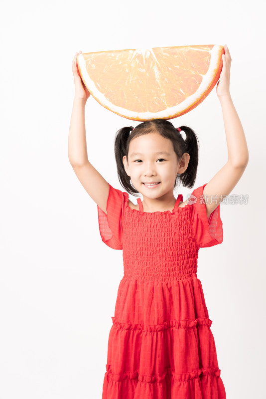站在白色背景前拿着橙子玩具的女孩