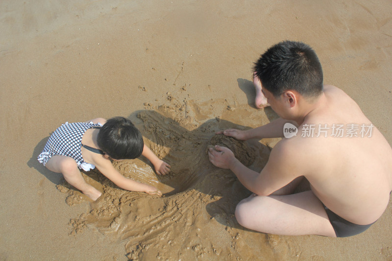 沙滩上爸爸与女儿一起玩沙子