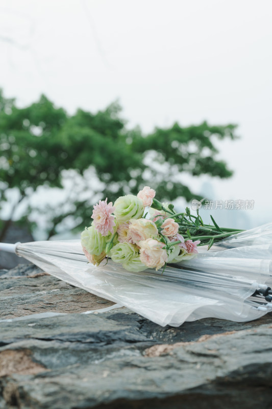 岩石上的花束与透明雨伞