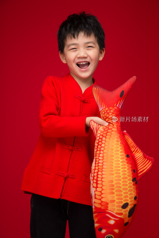 红色背景下拿着鱼的中国小男孩