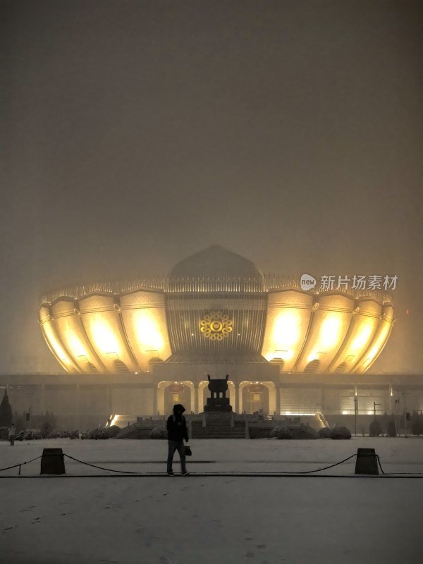 雪夜中建筑前行走的人