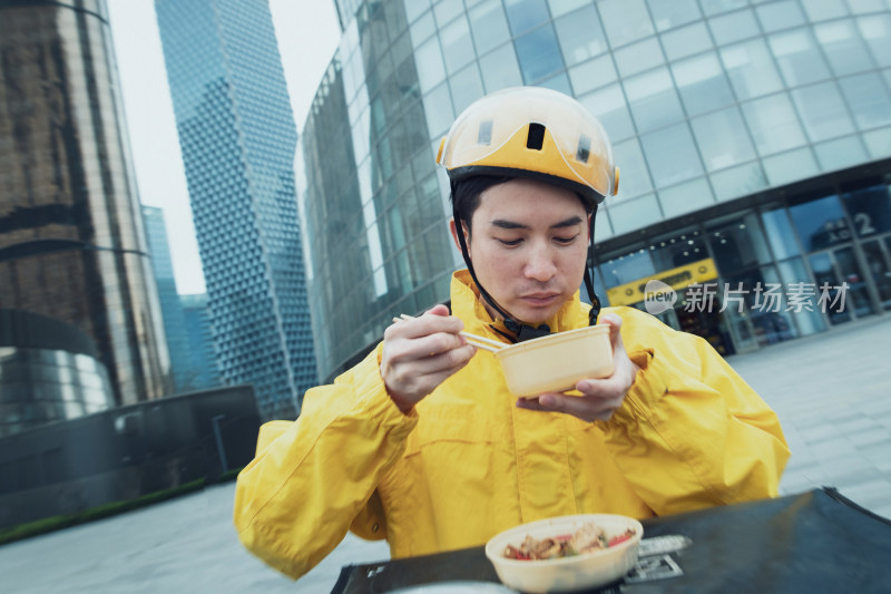 在户外吃饭的青年外卖员