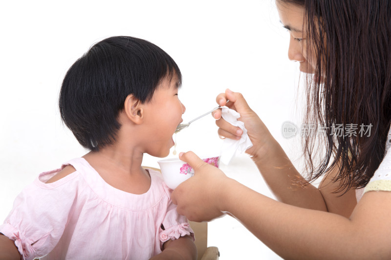 白背景前年轻妈妈正在给孩子喂饭