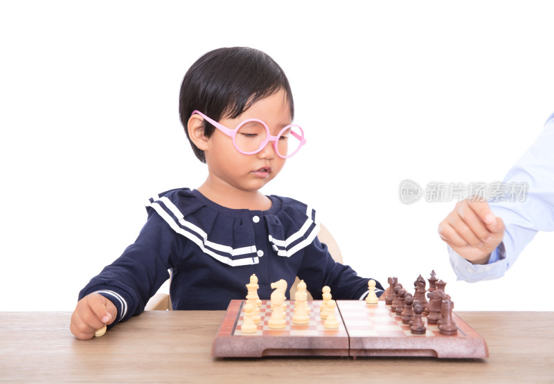 戴着眼镜框的中国小女孩在认真的下国际象棋