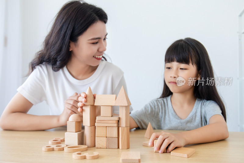 一位中国妈妈陪伴女儿玩积木