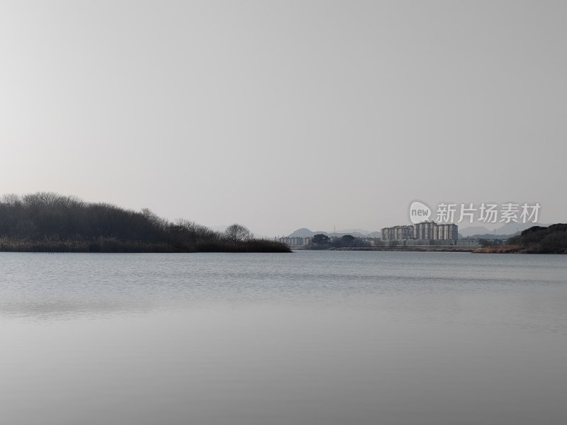 平静湖面及岸边树木和建筑的自然风光