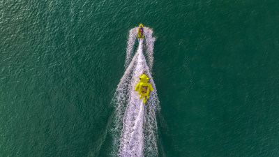 航拍俯瞰威海金海滩海水浴场快艇拖曳大黄鸭