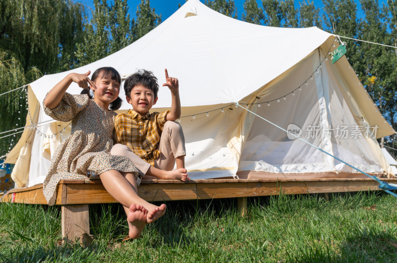 两个孩子坐在帐篷外玩耍