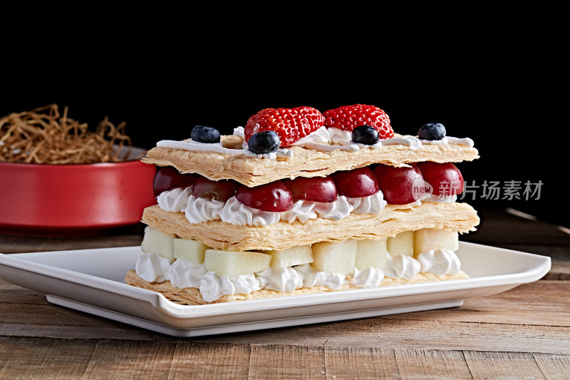白色瓷盘装的水果戚风奶油拿破仑蛋糕