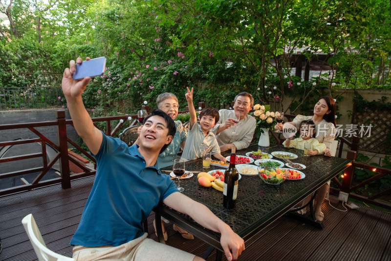 庭院里用餐的大家庭使用手机自拍