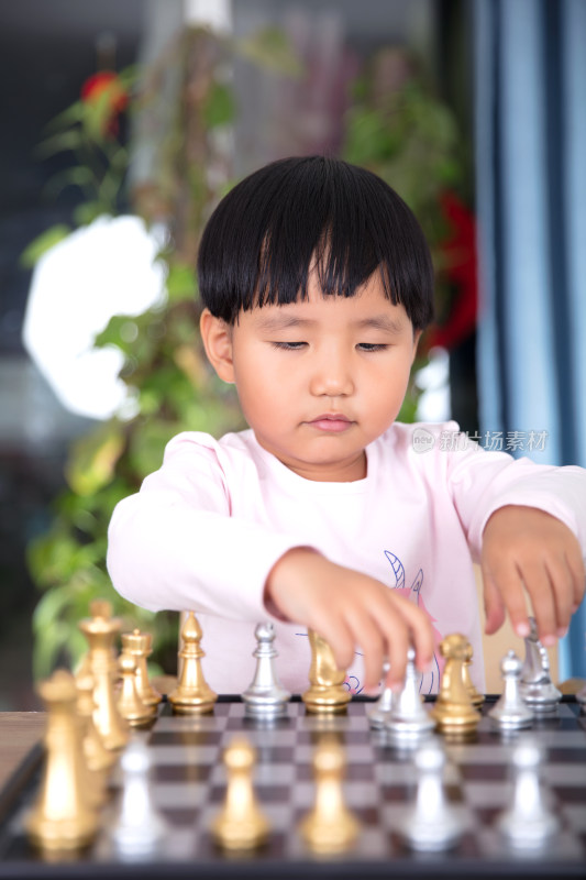 可爱的中国小女孩在学习下国际象棋