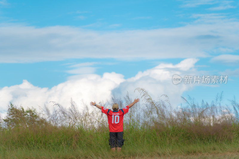 背对着天空站在草地上的人的后视图