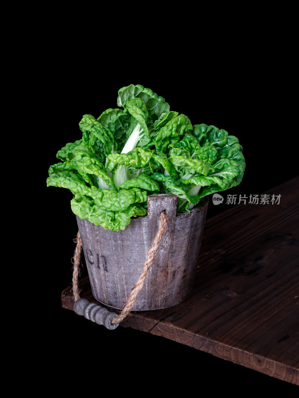 木桌角篮子中装着新鲜绿色蔬菜