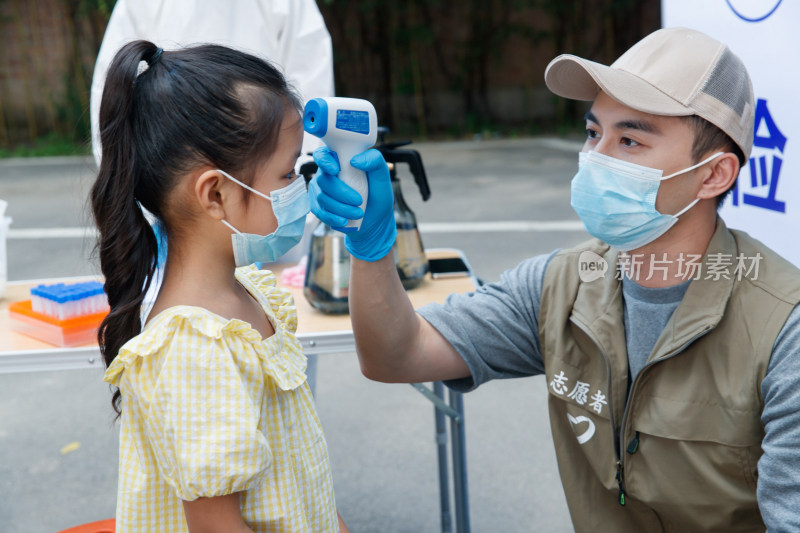 社区志愿者给小女孩测体温