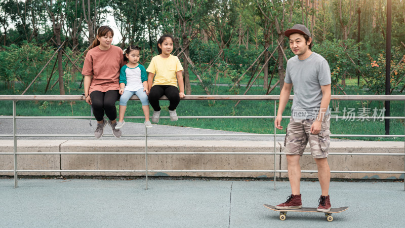 夏天在公园玩滑板的一家人
