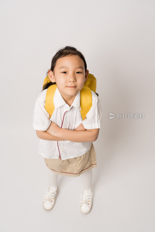 俯拍白色背景前背书包的中国女孩