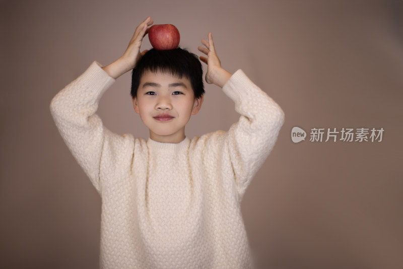 一个帅气的中国小男孩头顶着苹果