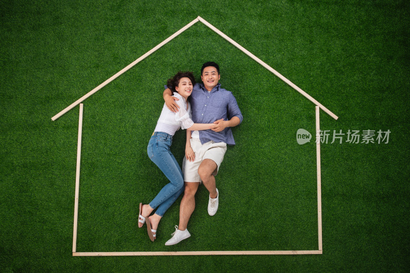 青年伴侣躺在草地上的房子轮廓里