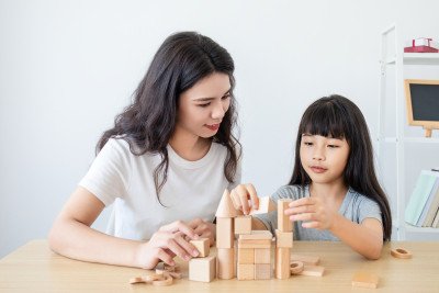 一位中国妈妈陪伴女儿玩积木