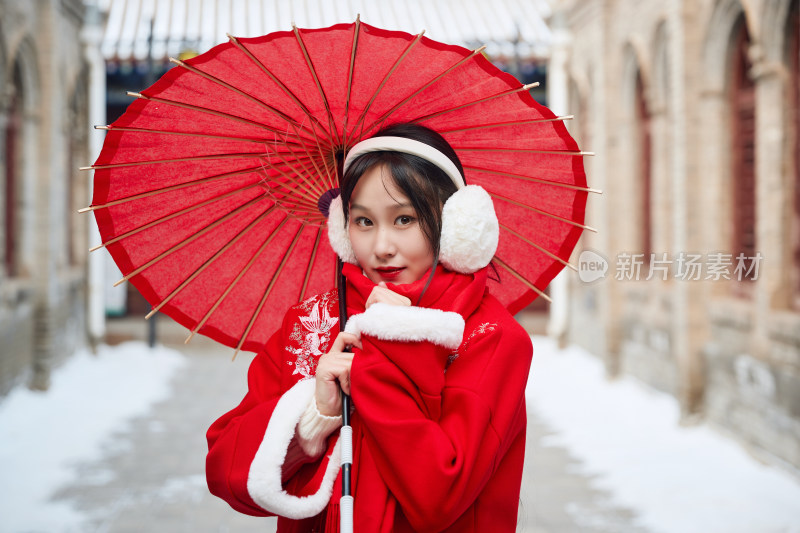 雪后在老城古巷穿着喜庆服饰的亚洲少女