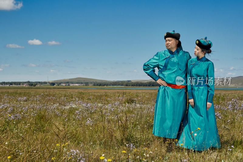 草原上蒙古包前穿蒙古族传统服饰的年轻夫妻