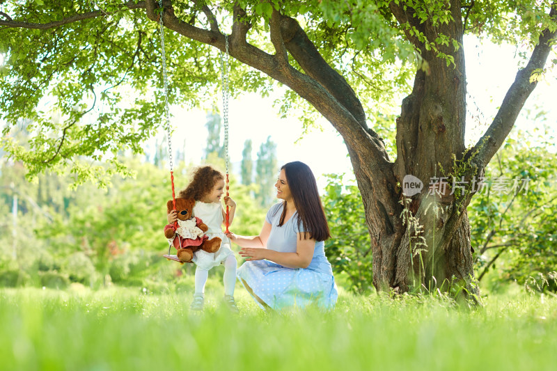 母亲与女儿在树下荡秋千场景