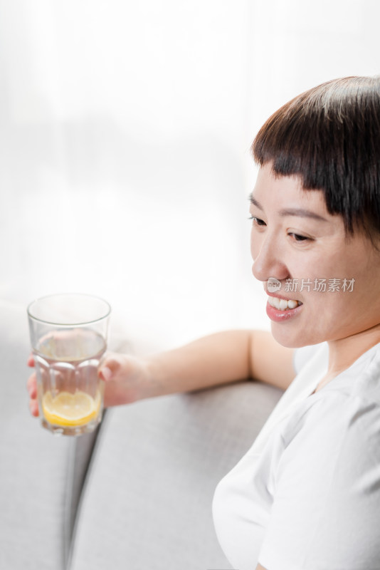 坐在沙发上喝水休息的中国女性