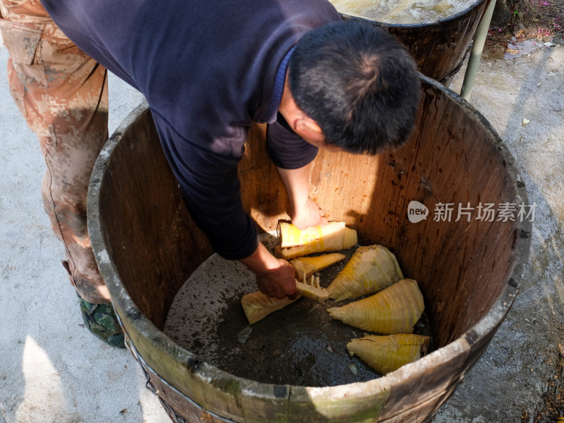 男子在木桶中处理竹笋的劳作场景