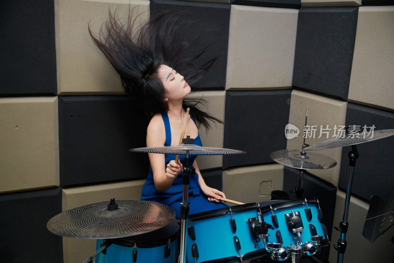 在排练室打爵士鼓的亚洲少女