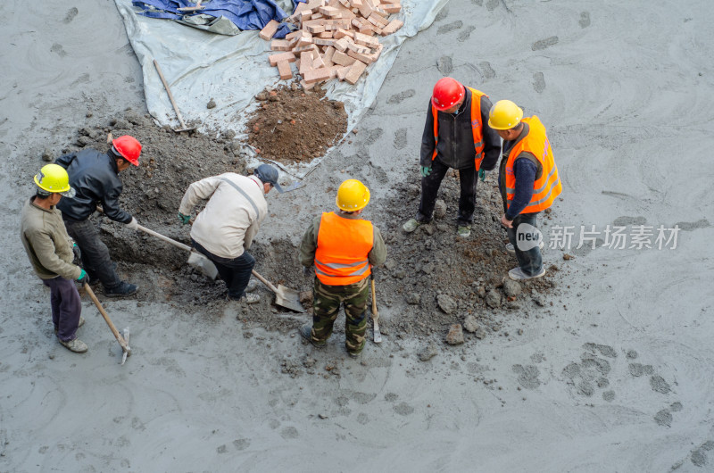 建筑工地上几个合作挖坑的建筑工人