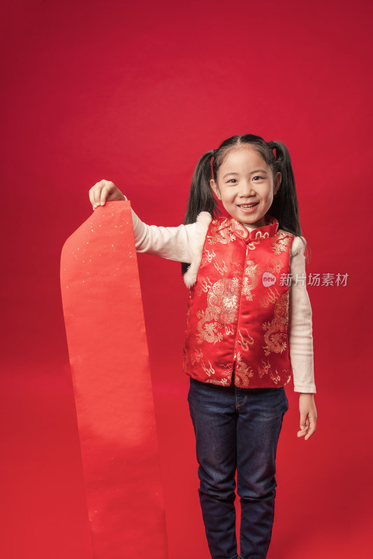 红色背景前穿唐装拿空白春联纸的中国女孩
