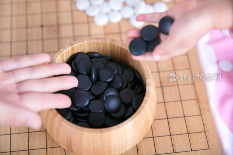 一只小手正把棋子放入棋盒中