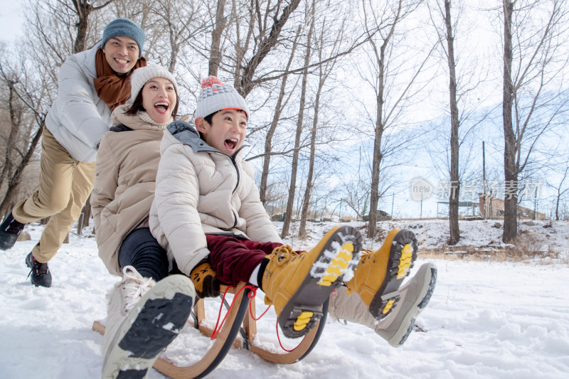 在雪地上玩雪橇的一家人