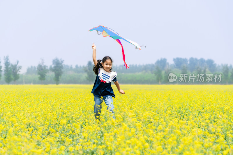 夏天拿着风车在油菜花田中奔跑的女孩