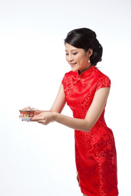 棚拍节日身穿红色旗袍的年轻女人端着茶杯