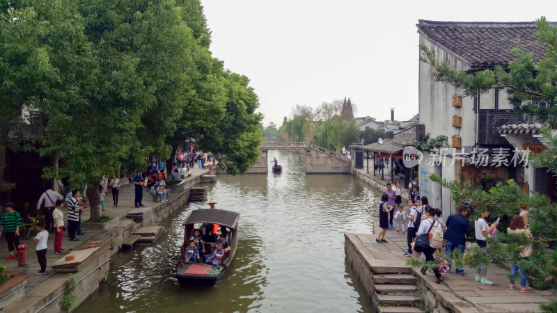 江南水乡河道边游人乘船景象