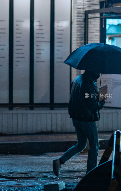 雨夜中撑伞行走的行人剪影