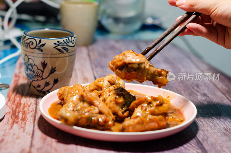 夹起一块鸡腿肉，一个中国传统花纹陶瓷水杯