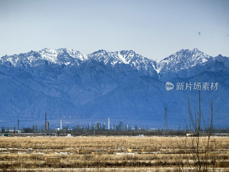 雪山下的开阔田野与工业设施