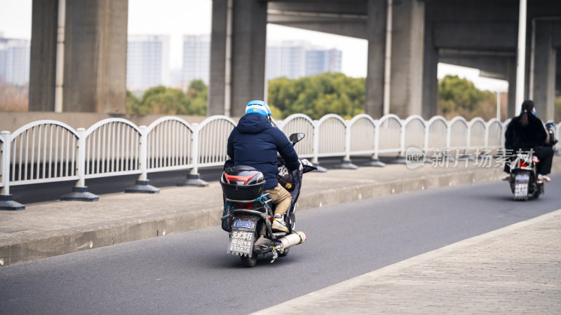 骑摩托车的人在有护栏的道路上行驶