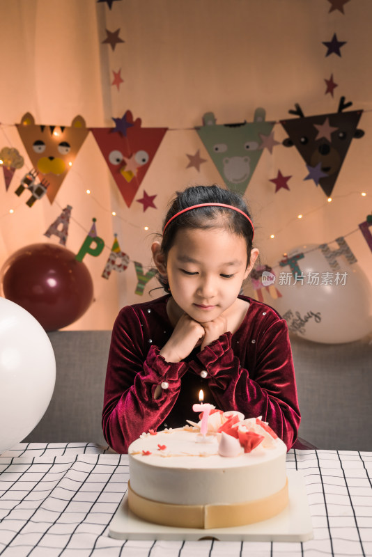 中国女孩对着生日蛋糕许愿吹蜡烛