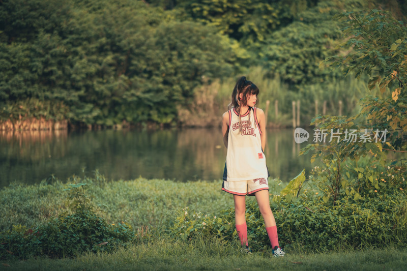 傍晚穿篮球服站在公园里的少女