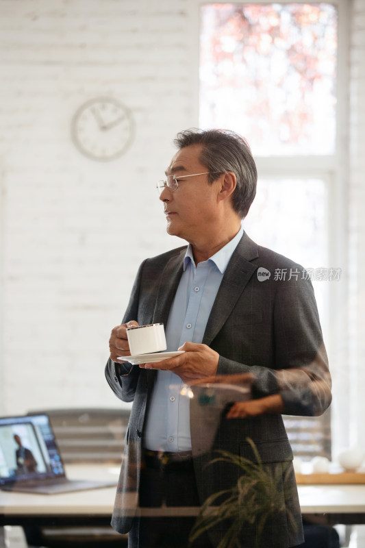 会议室内端着咖啡杯的商务老年男士