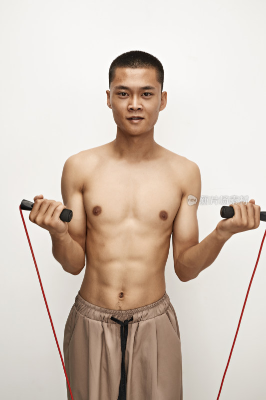 白色背景下手持运动跳绳的亚洲健身男士形象